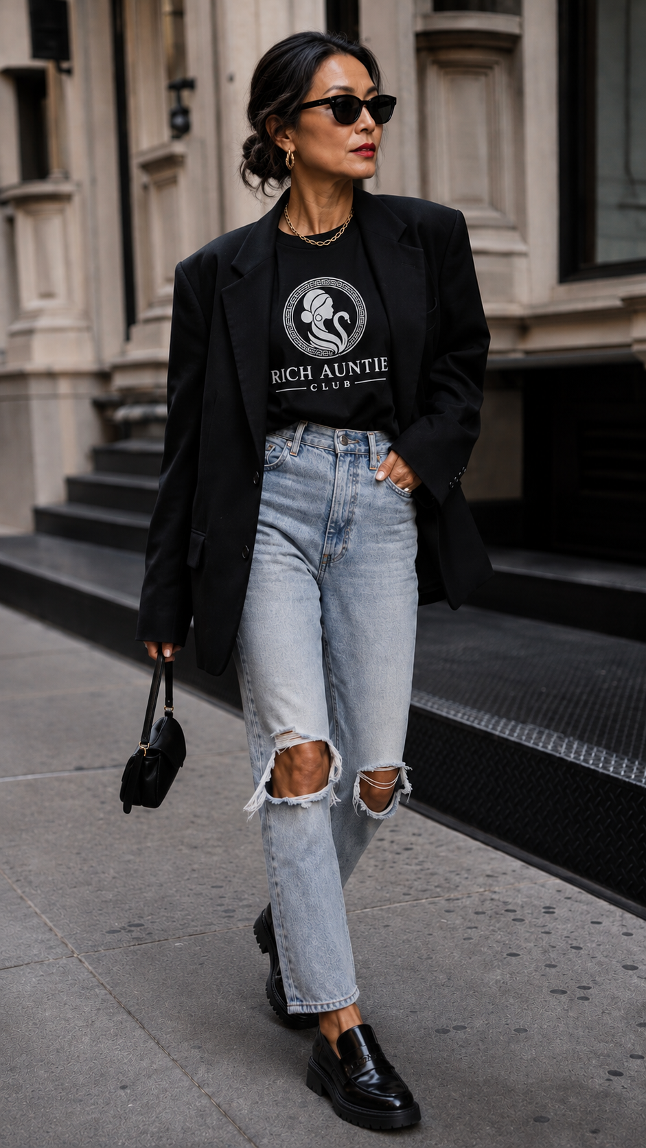 Woman wearing black VERS✦CE inspired Rich Auntie Club tee with black blazer and jeans